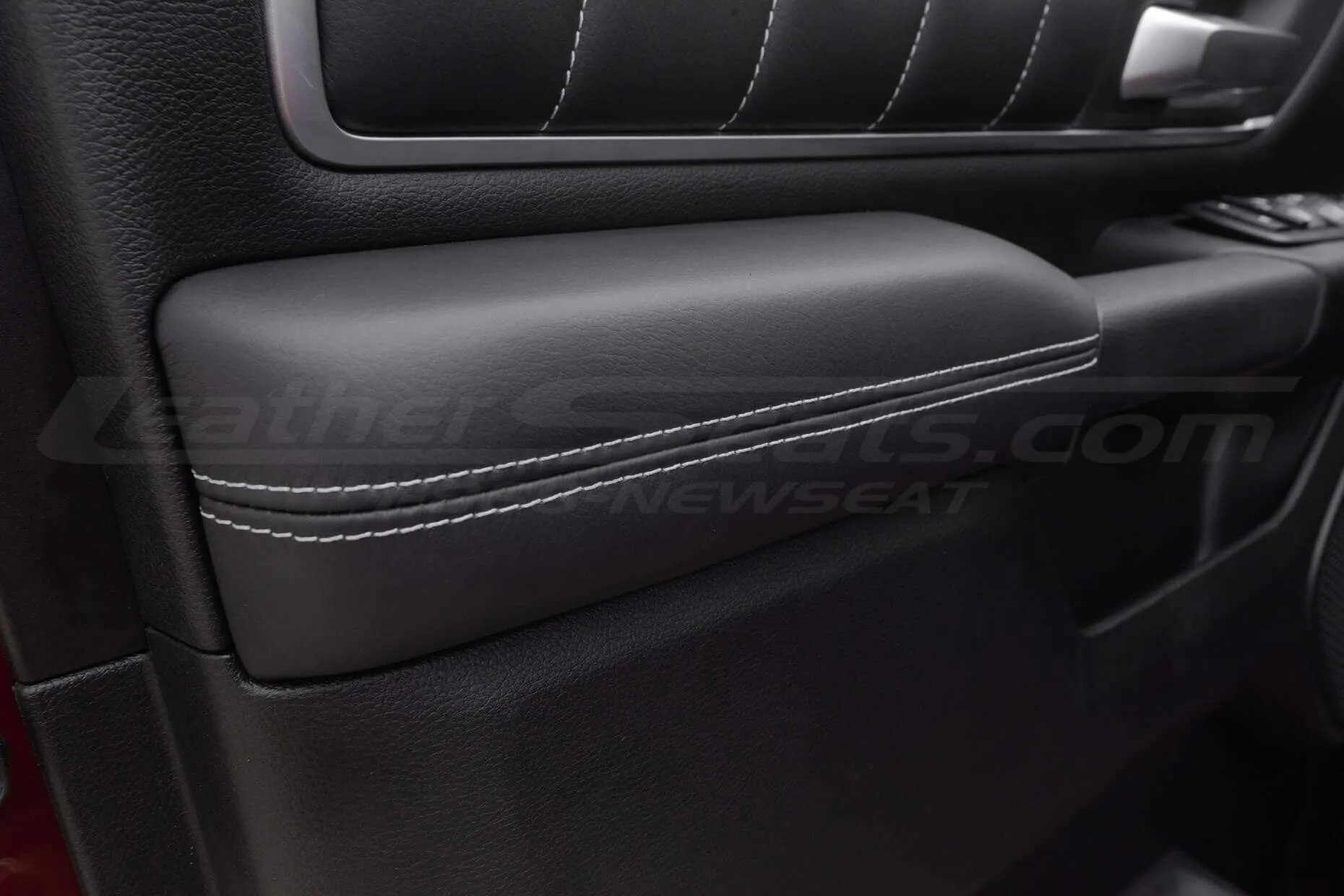 Black leather door armrest with ocntrasting white double-stitching
