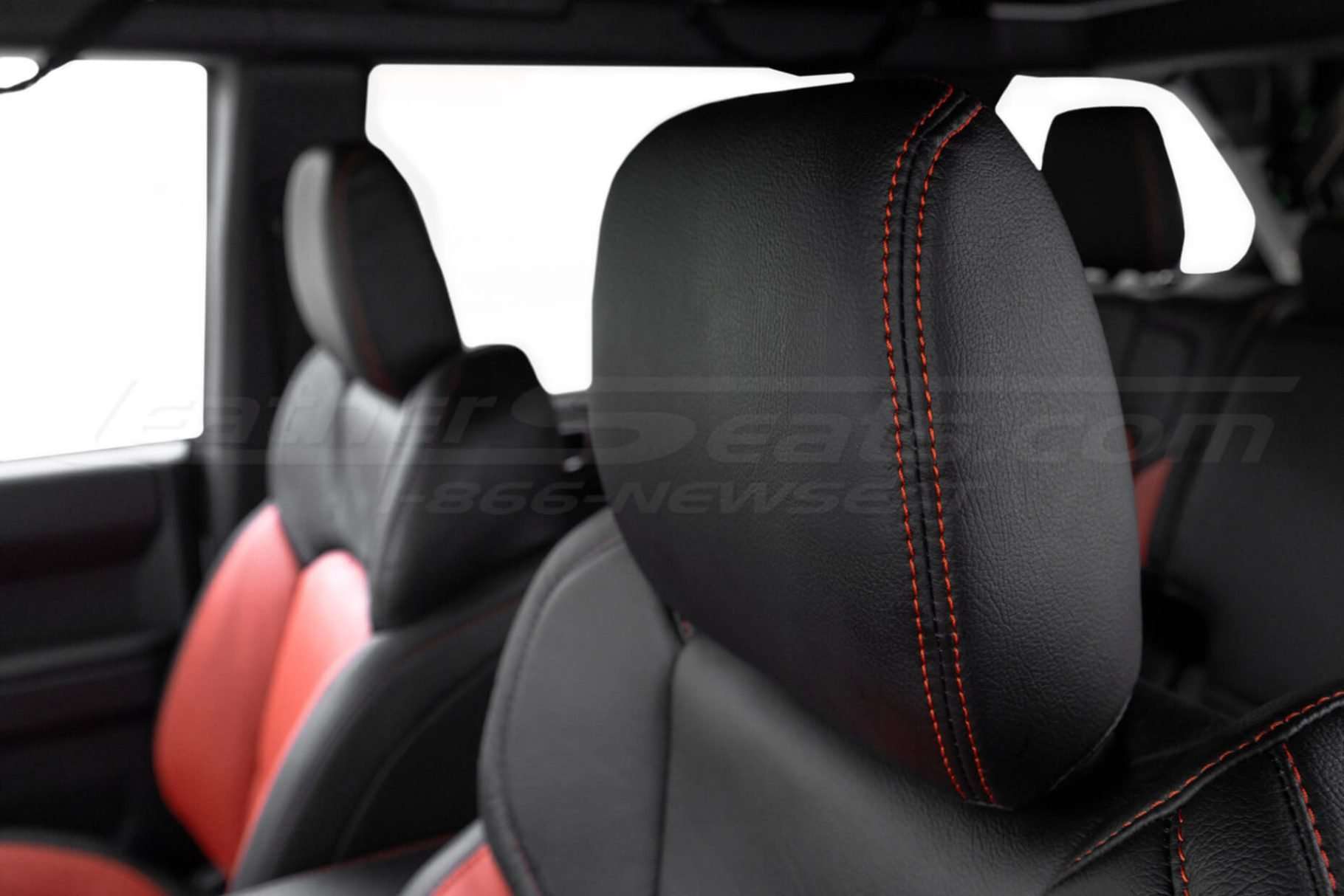 Black leather headrest close-up with contrasting double-stitching in tangerine