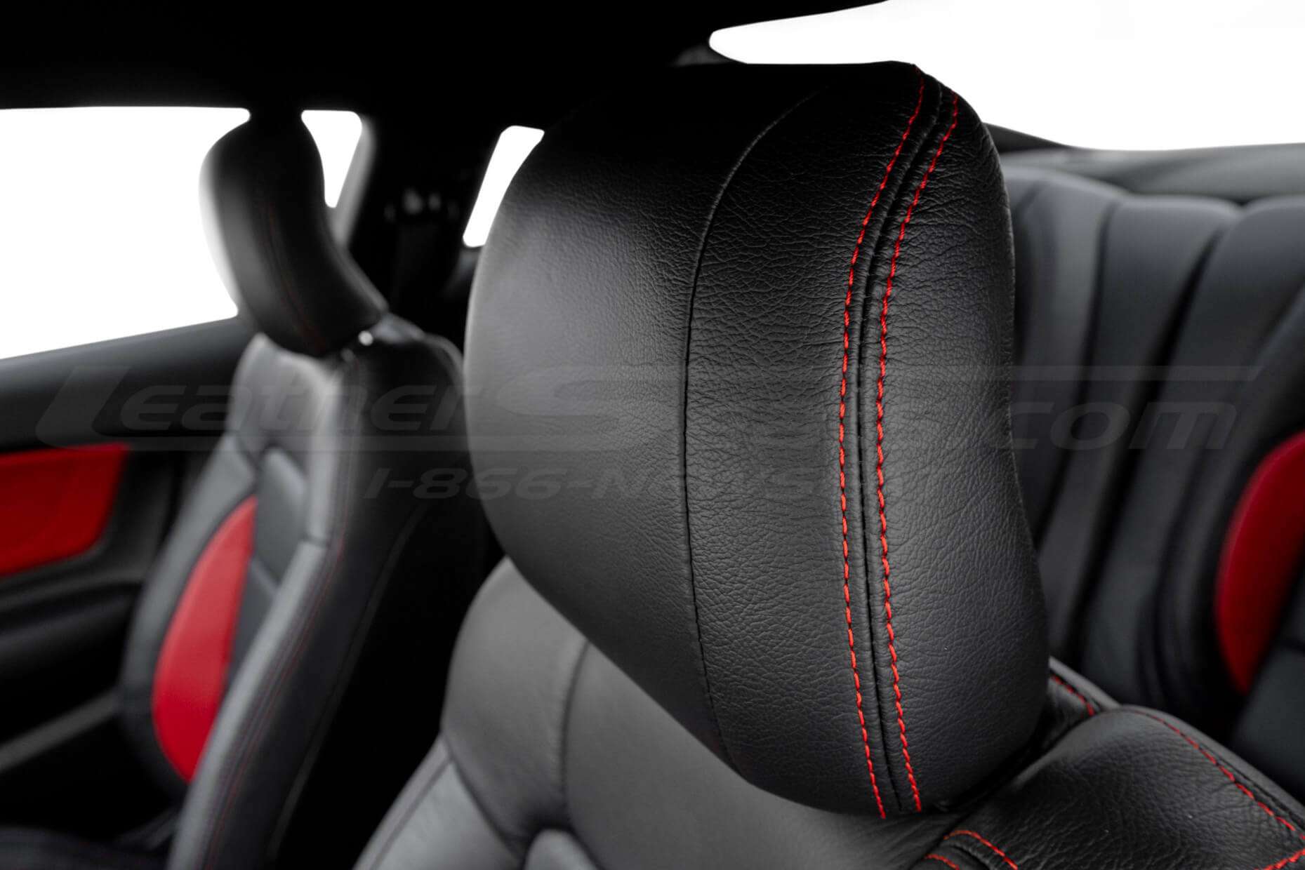 Black leather headrest close-up with bright red stitching