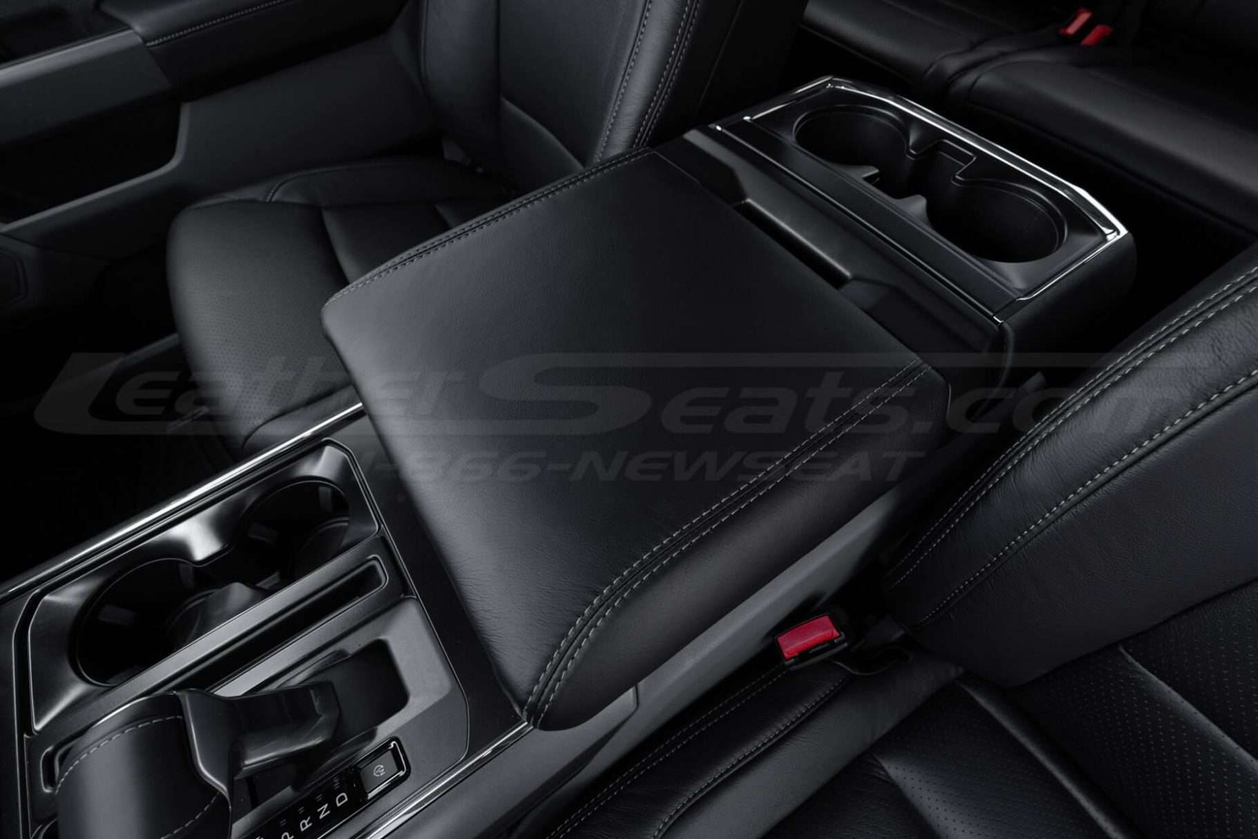Driver side close-up of Ford F-150 black leather console lid cover with ston stitching
