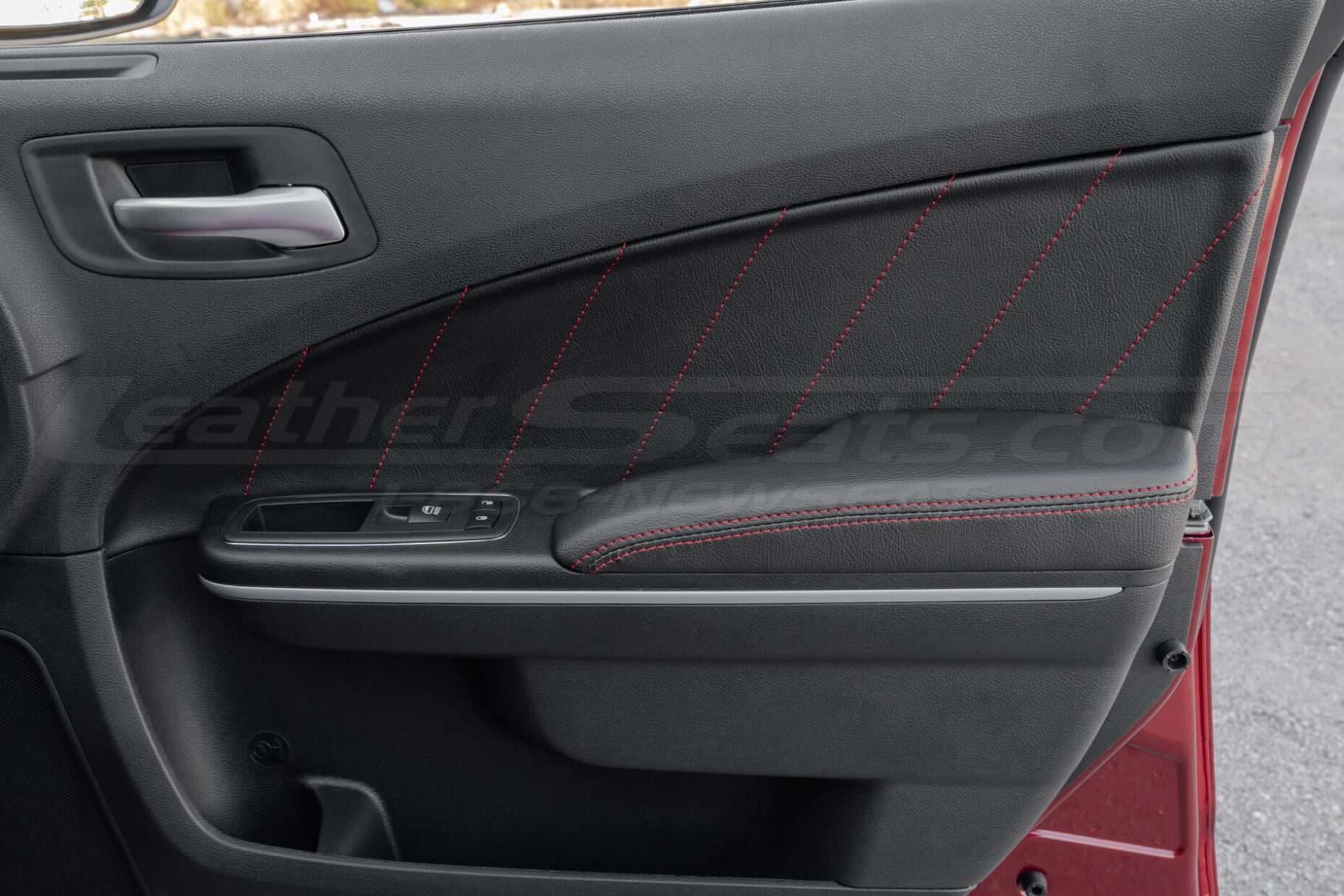 Front passenger door of Dodge Charger with leather door inserts and armrests in black leather with red stitching
