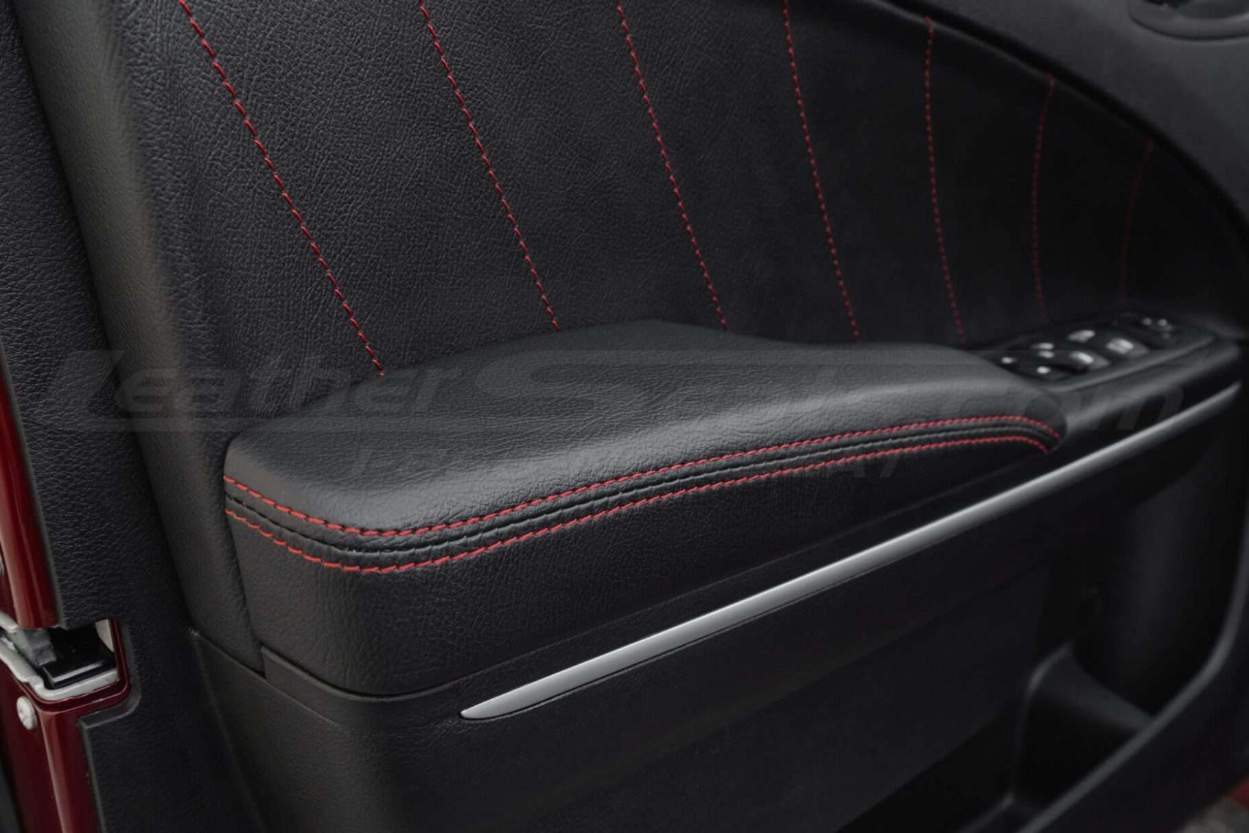 Close up of leather door armrest upholstery in blck leather with red stitching