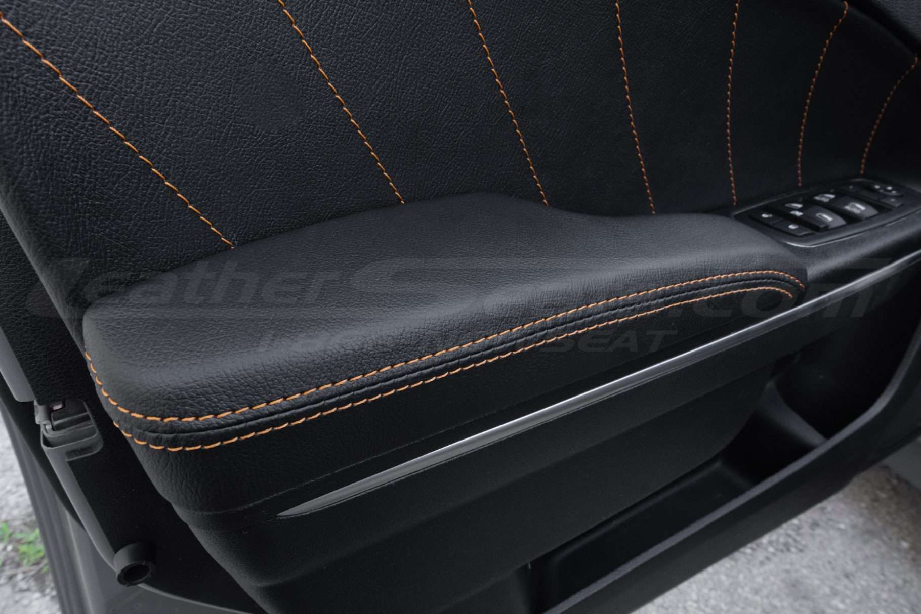 Black leather door armrest with contrasting orange stitching - front driver door installed