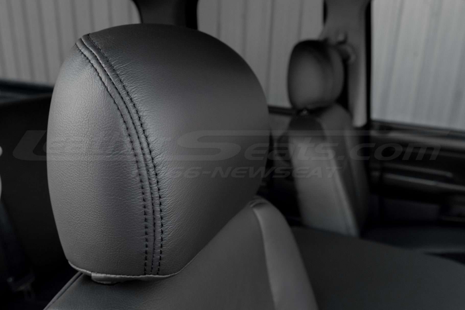 Dark Graphite installed leather headrest close-up with dark graphite stitching