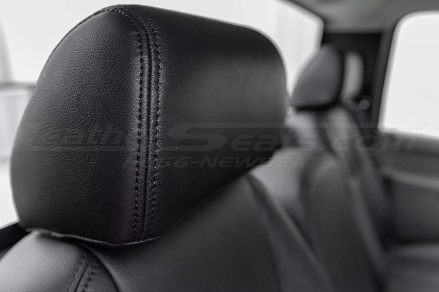 Installed black leather headrest close-up with matching black double-stitching