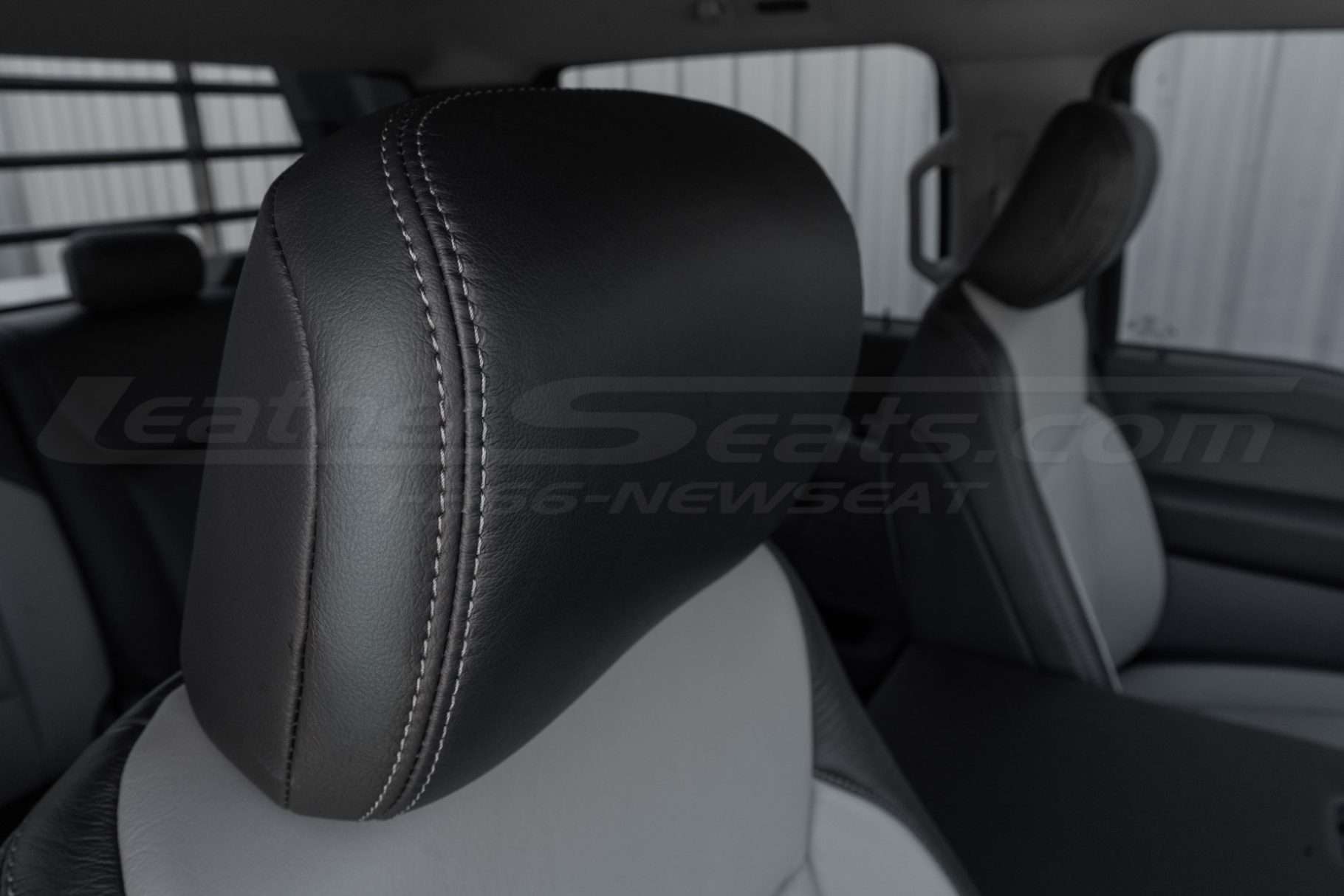 Installed black leather headrest close-up with contrast Ash stitching