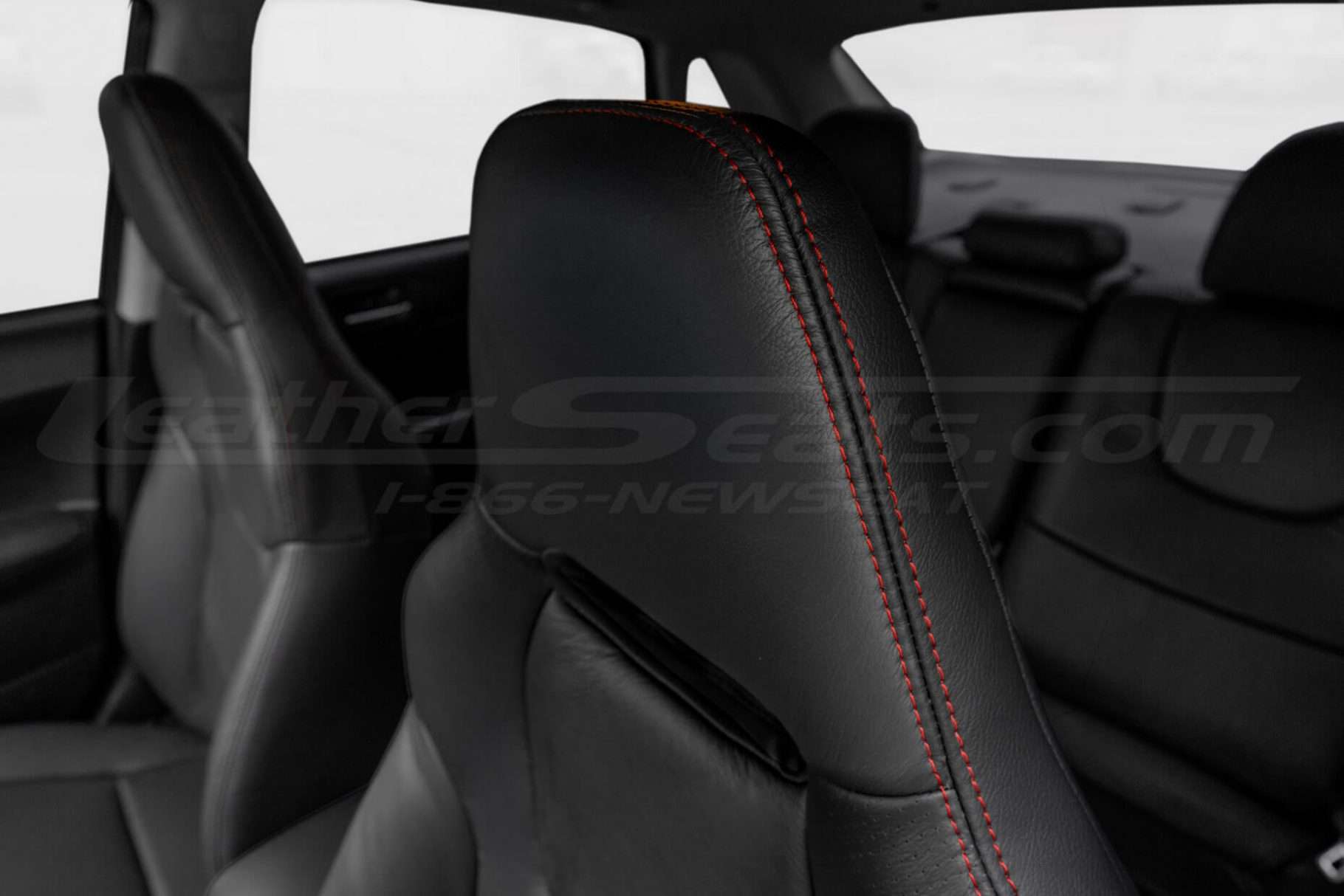 Black leather headrest close-up with contrasting Red double-stitching