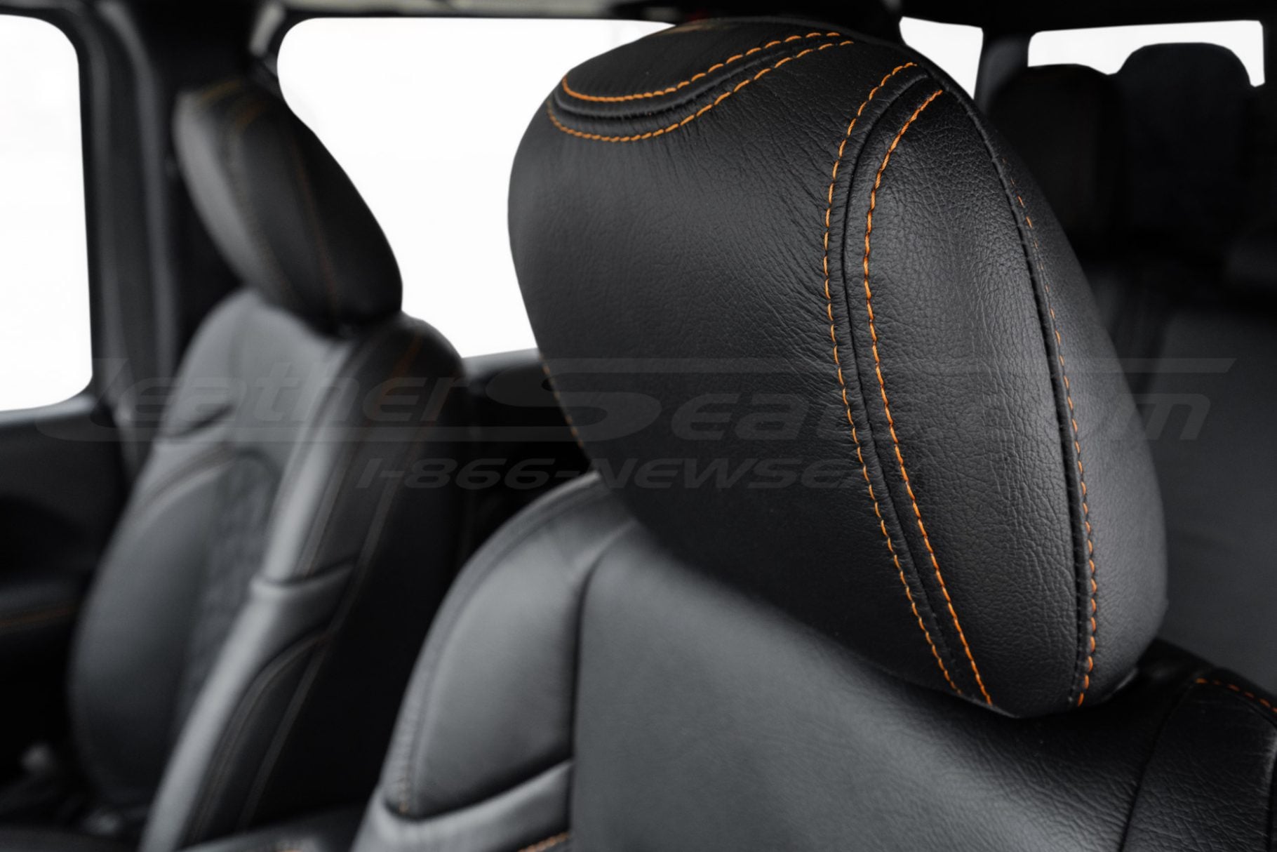 Black leather jeep headrest close-up with contrast orange stitching