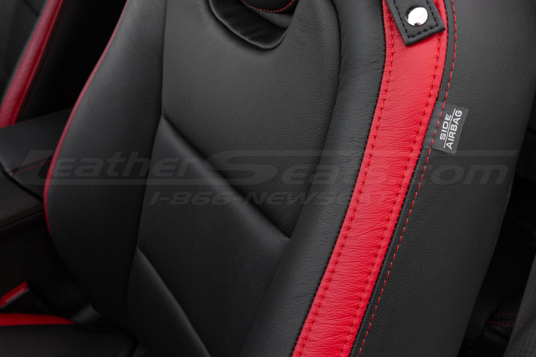 Close-up of Chevrolet Camaro black leather seat with red stitching and side airbag label