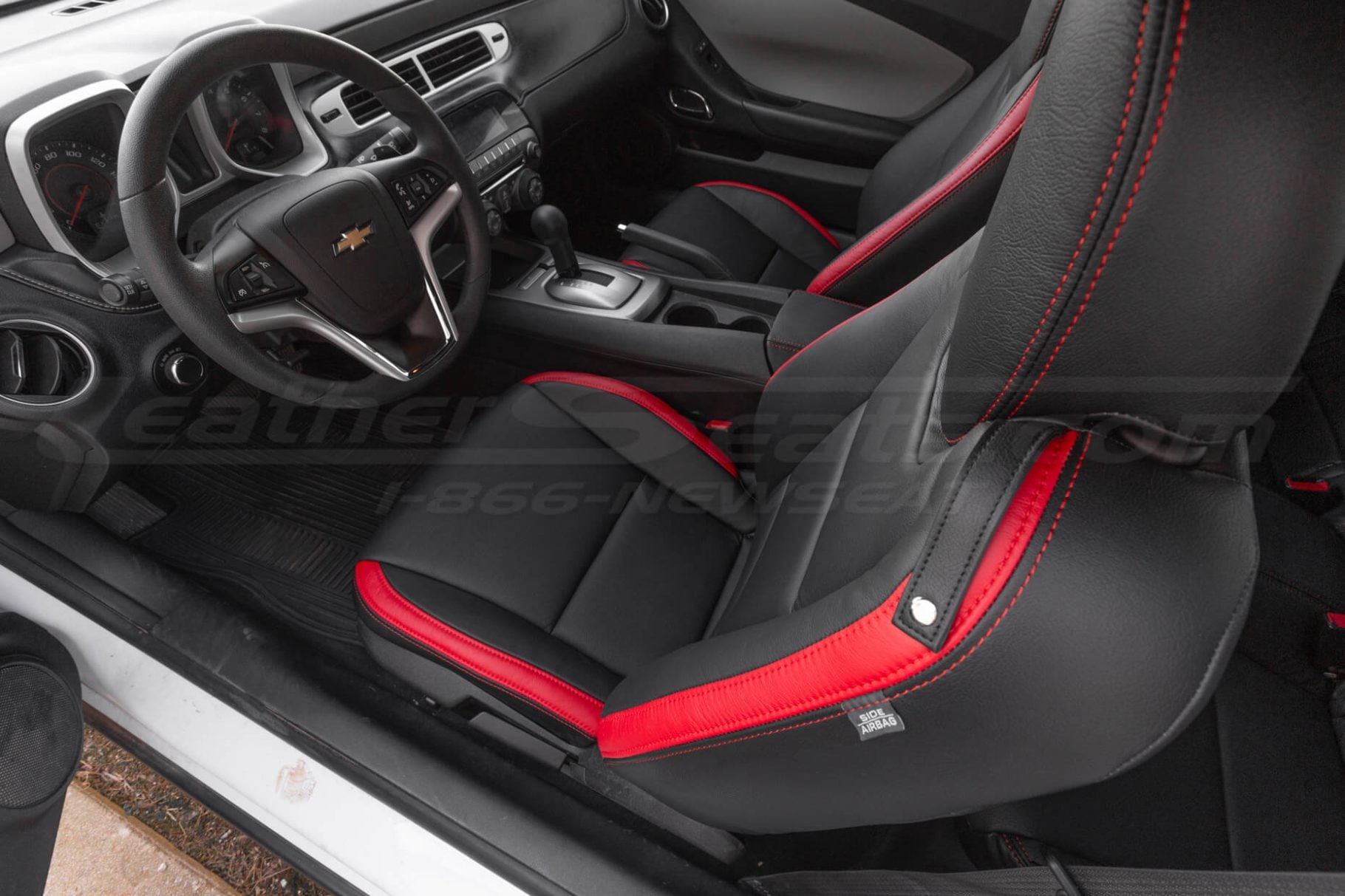 Driver's perspective inside a Camaro, highlighting the black and red sport seats and steering wheel