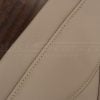 Close-up of beige leather seat cover with double-stitched seam and fine grain texture.