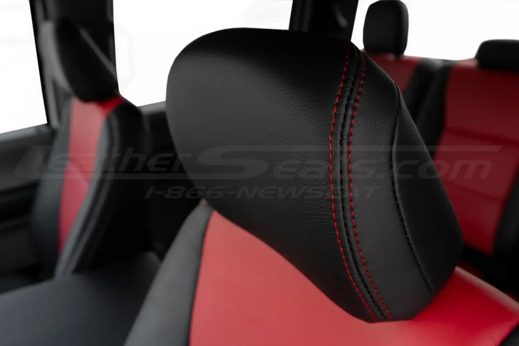 Black leather headrest close-up with contrast red double stitching
