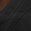 Close-up of light grey double stitching on black leather