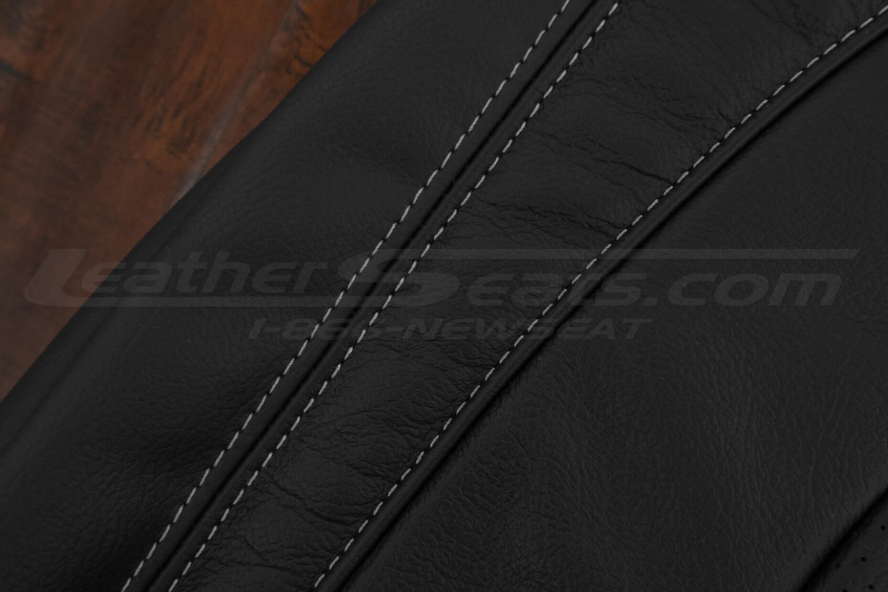 Close-up of light grey double stitching on black leather