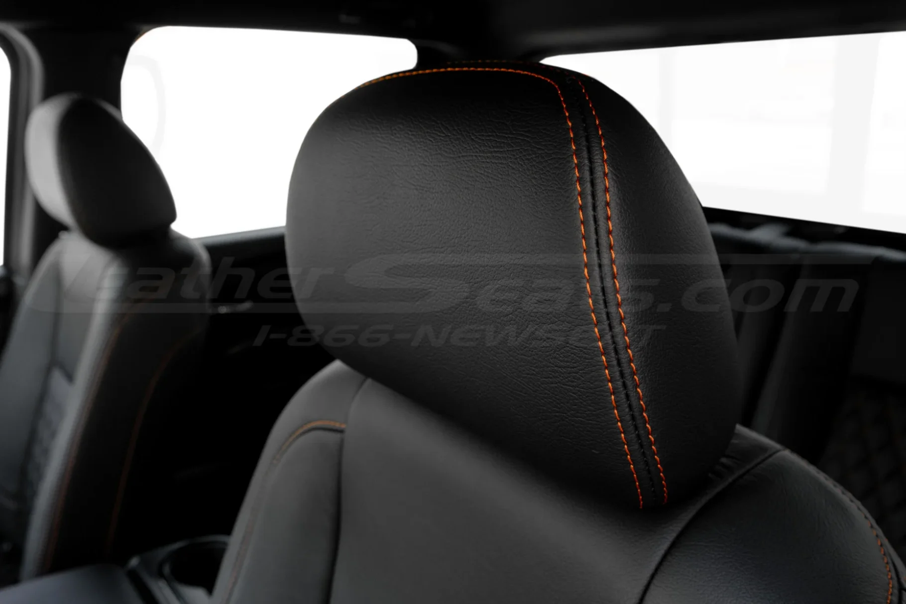 Nissan Titan black leather headrest with orange stitching close-up